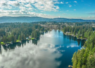 green trees near lake under white clouds and blue sky during daytime