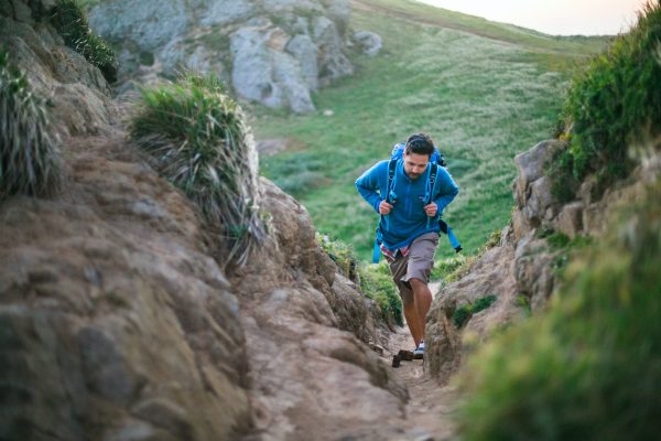 Photo by Kitera Dent man in blue t-shirt and blue shorts running on brown rocky mountain during daytime