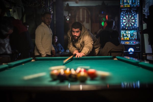 Photo by Carla Oliveira man in brown jacket playing billiard