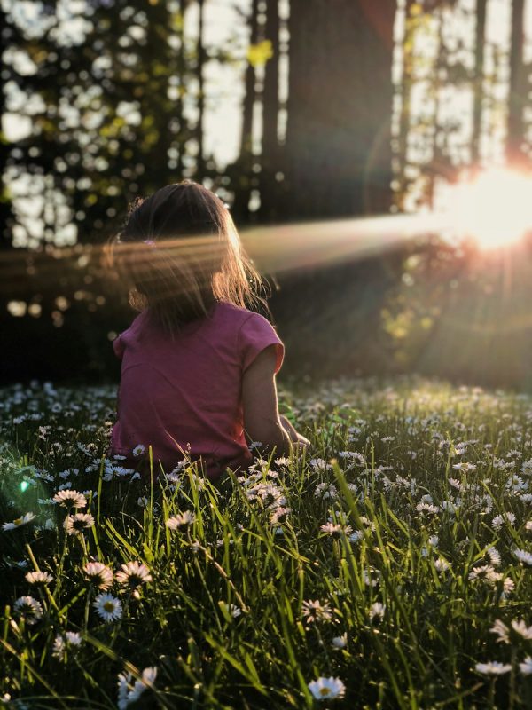 Photo by Melissa Askew girl sitting on daisy flowerbed in forest