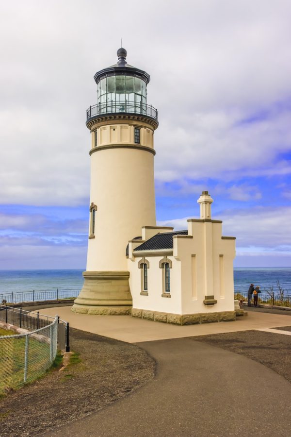 Photo by AMANDA CHAPMAN a light house sitting on top of a hill next to the ocean